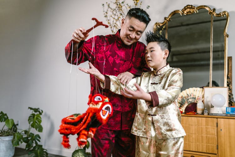 A Man Teaching A Boy How To Use A Chinese Lion Puppet