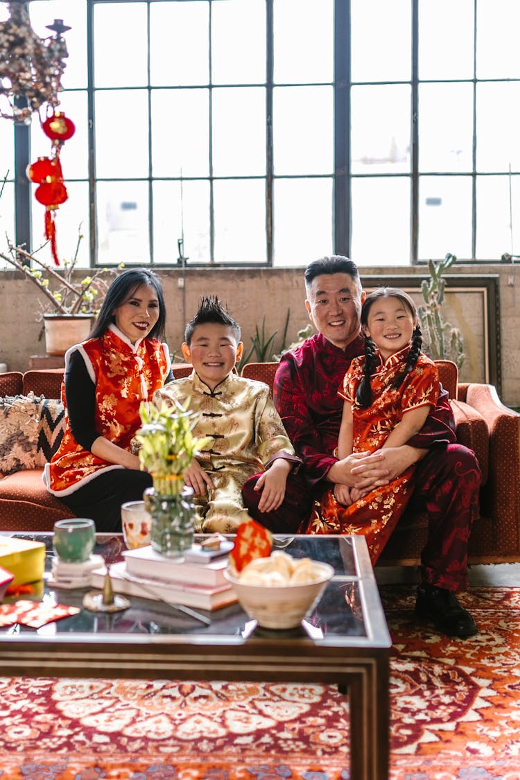 Happy Family Sitting Together On Red Sofa