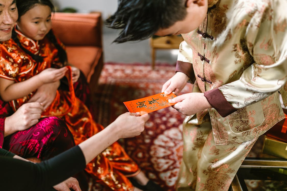 Family moment with parents in traditional attire giving a red envelope to a young boy during Lunar New Year celebrations