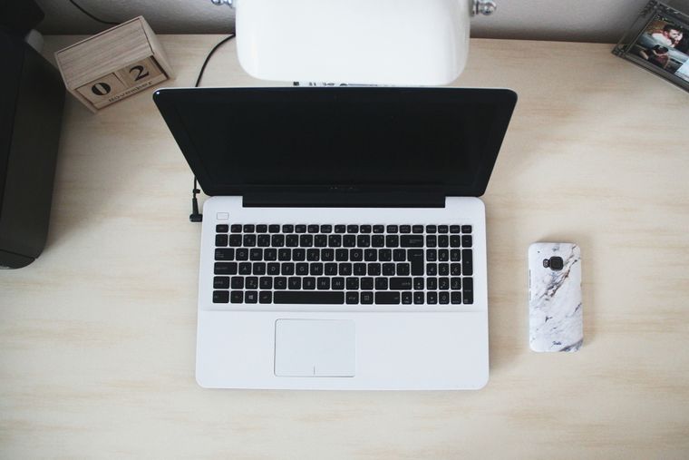 Laptop open on a desk beside a notebook — photo by Dominika Gregušová on Pexels
