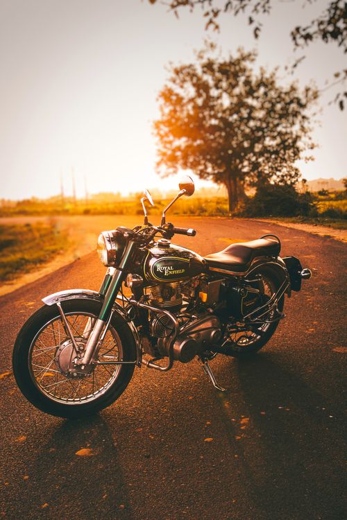 Free Vintage Royal Enfield motorcycle parked on a rural road at sunset in Brahmabarada, India. Stock Photo