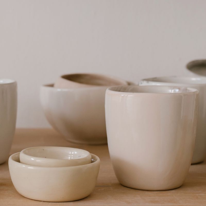 Pale handmade plates and bowls on a wooden table