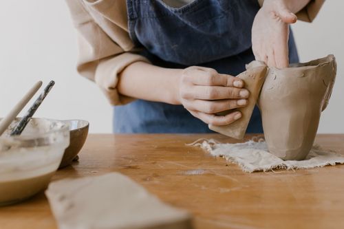 Free Close-up of hands shaping clay at a pottery worktable, showcasing the artistry of ceramics. Stock Photo