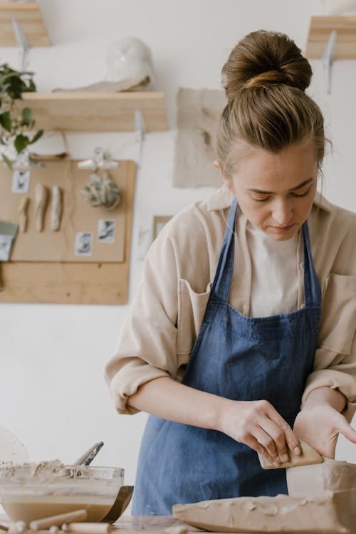 Woman in Beige Long Sleeves and Blue Apron Molding Clay