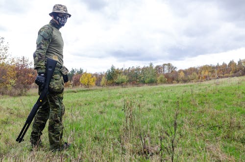 Photo of Man Wearing Green Combat Uniform Holding Rifle