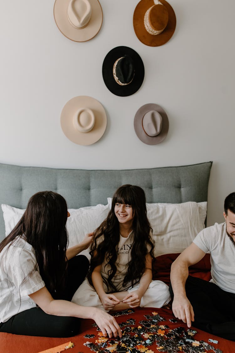 A Girl Playing With Puzzles With Her Parents On A Bed