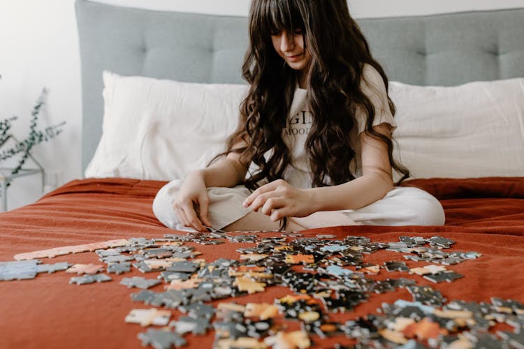 A Girl With Long Wavy Hair Putting The Pieces Of Puzzle Together