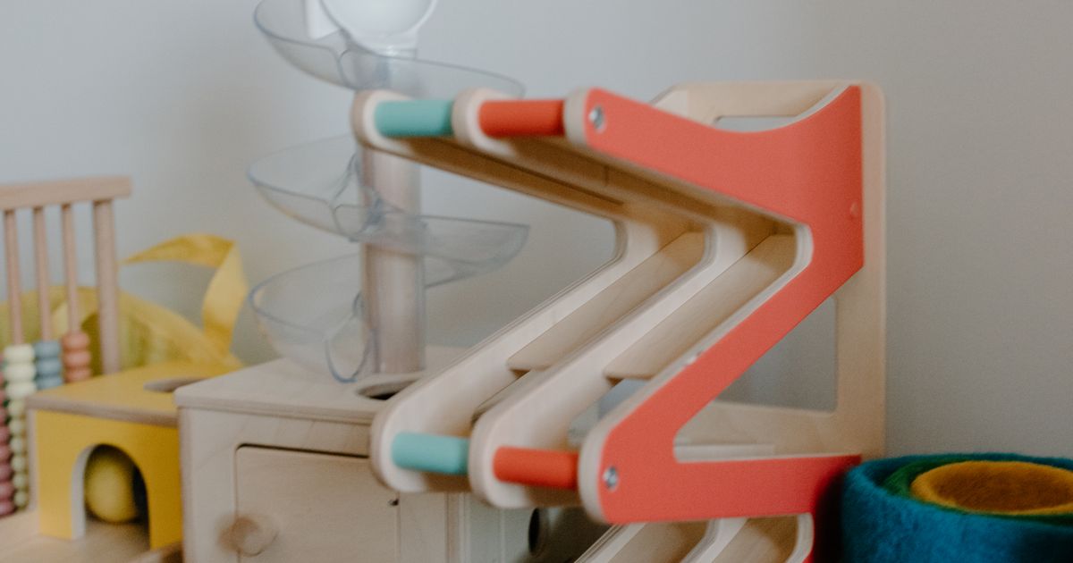 A wooden zig-zag ball run toy in a bright playroom