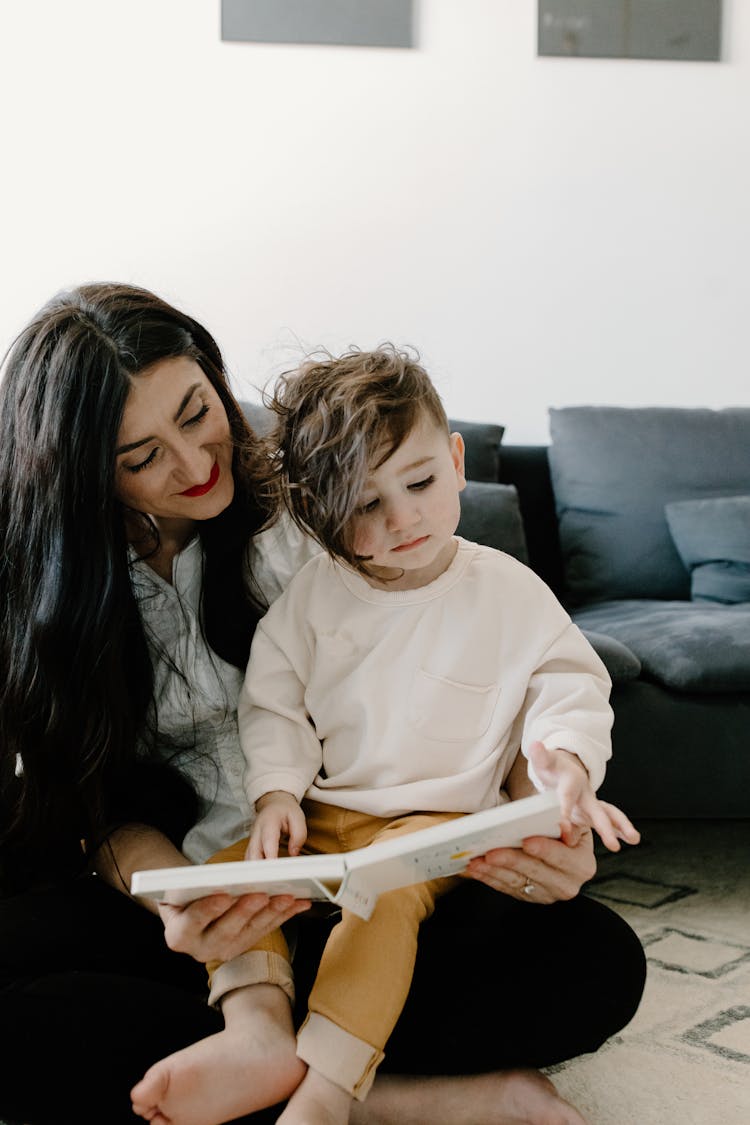 A Boy Reading A Book With Her Mother