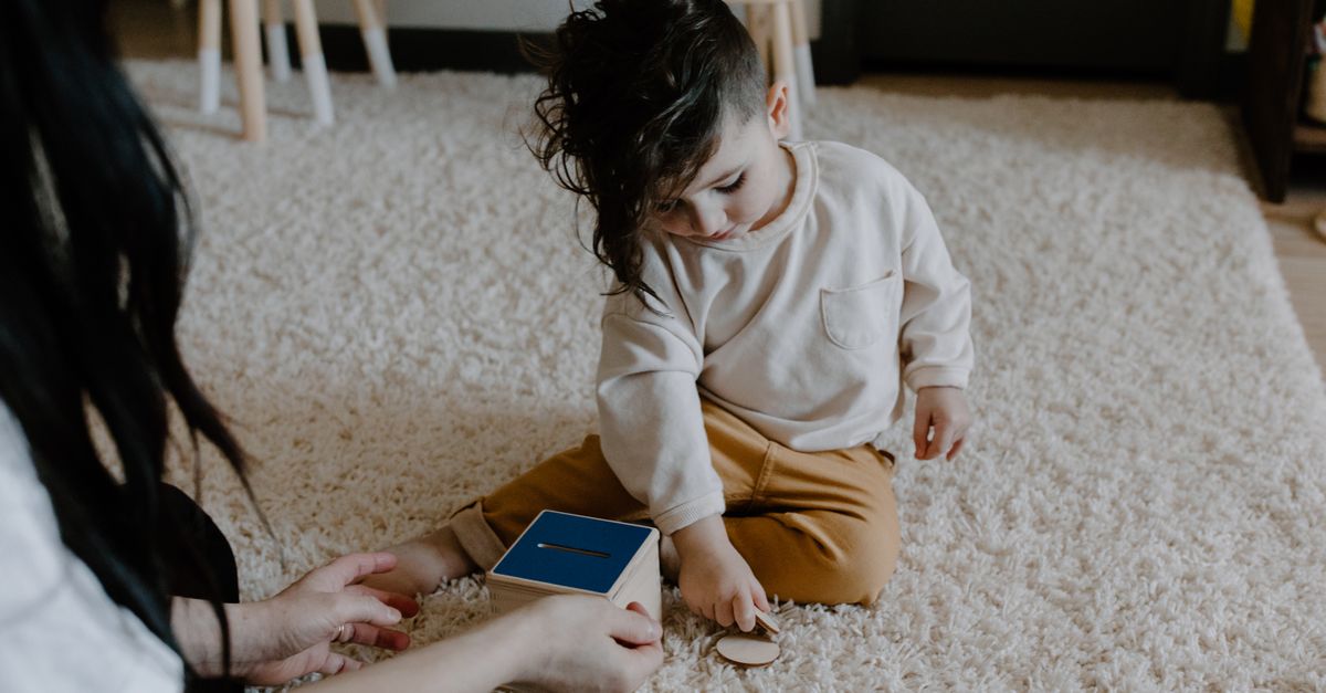 Un enfant s'amuse avec un jouet en bois éducatif sur un tapis doux à l'intérieur, mettant en valeur la créativité et l'apprentissage.