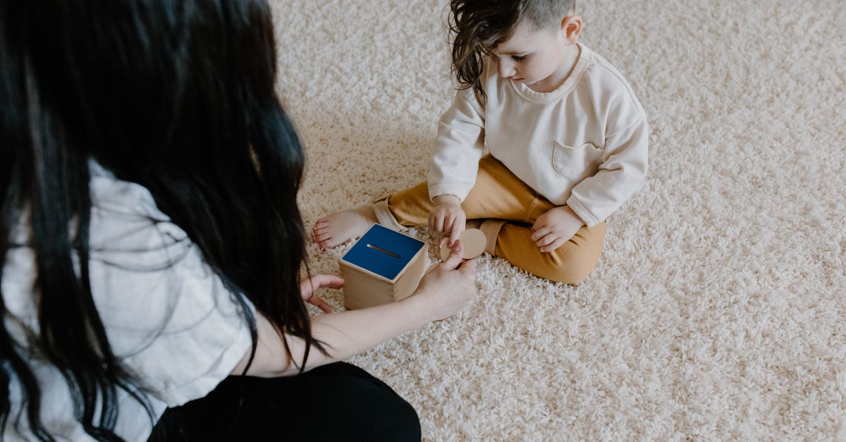 Un jeune enfant jouant avec un jouet éducatif en bois sur un doux tapis à l'intérieur.