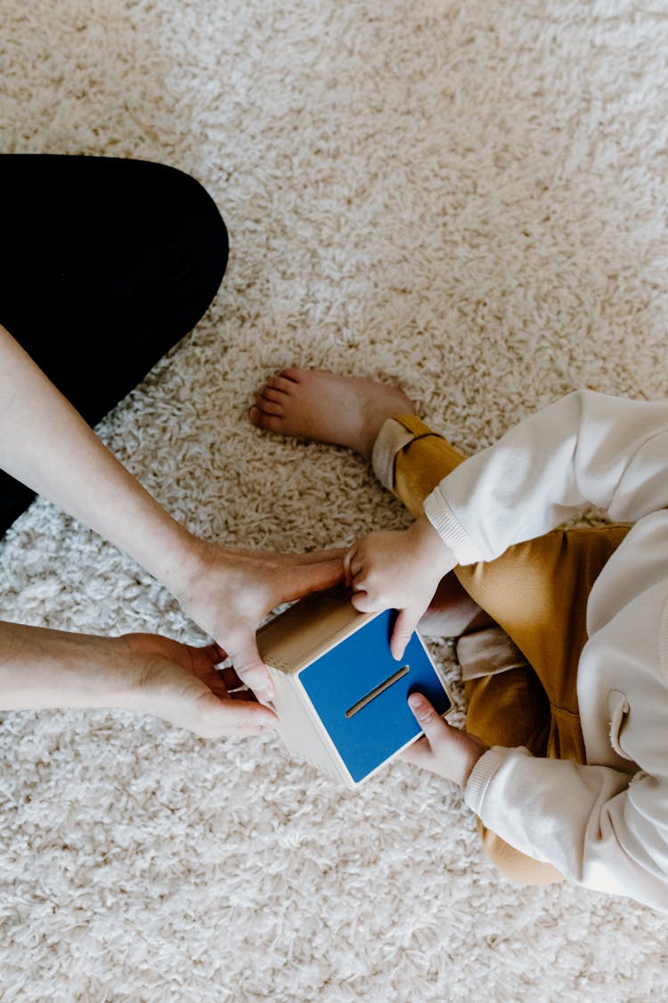 Top View Of A Person Handing An Educational Toy To A Child