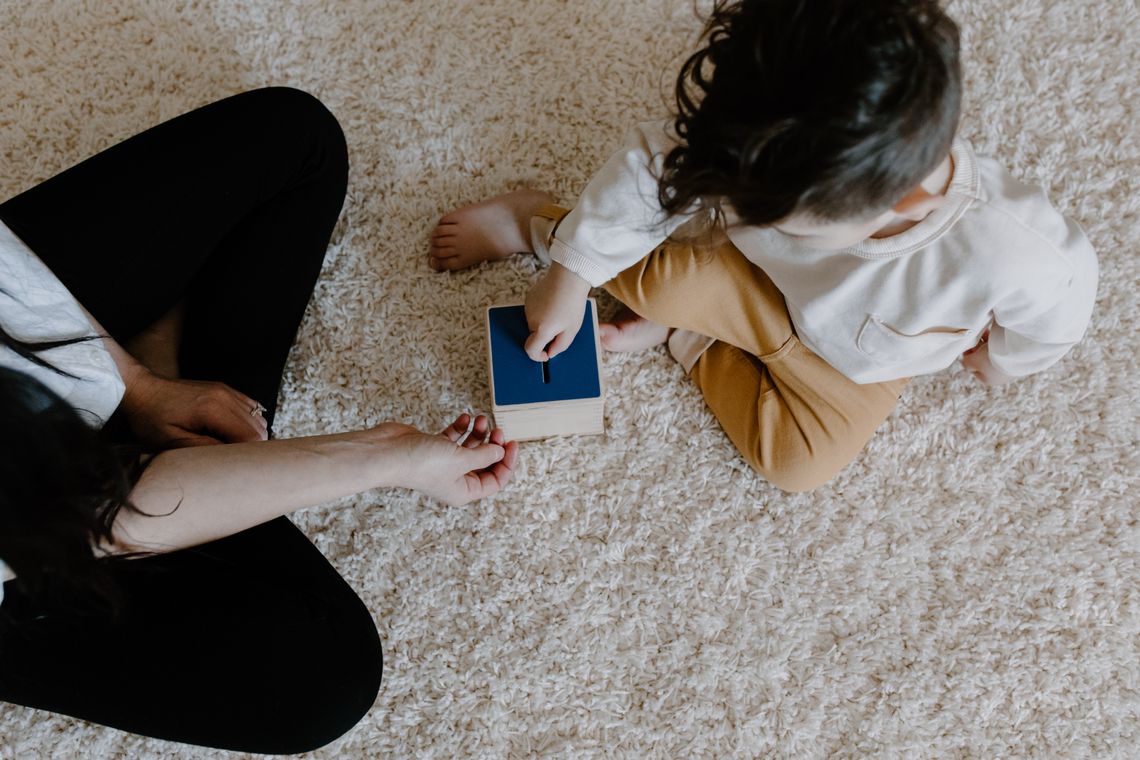 Mother and child carefully using a wooden educational toy together at home