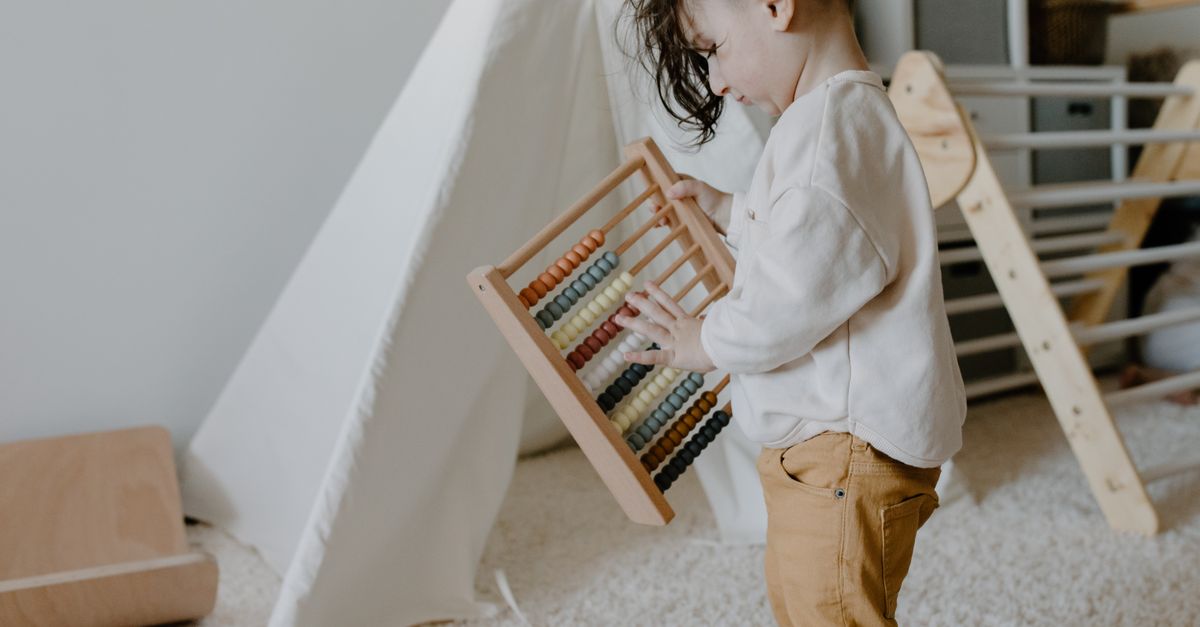 Un jeune enfant apprend avec un boulier en bois dans une ambiance de salle de jeux intérieure confortable.