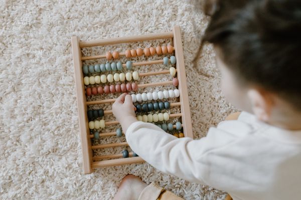 Child playing with an abacus on the floor