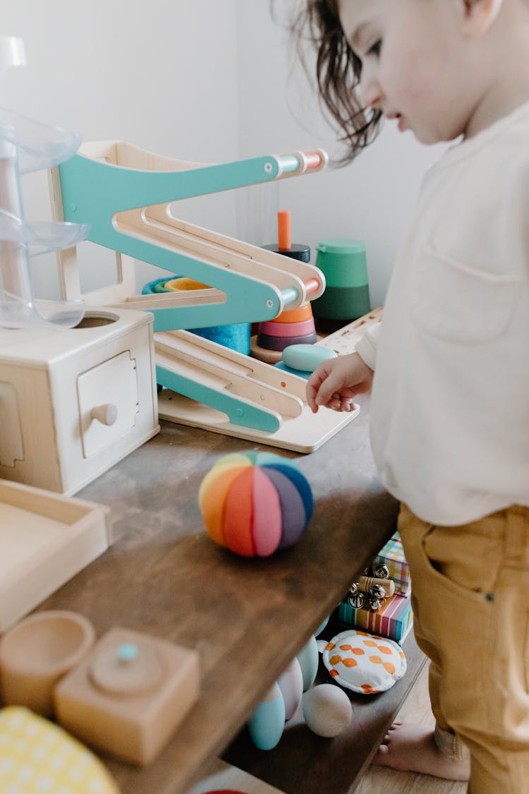 A Child Looking At His Toys On The Table