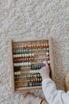 Overhead view of a child using a colorful wooden abacus on a carpet.