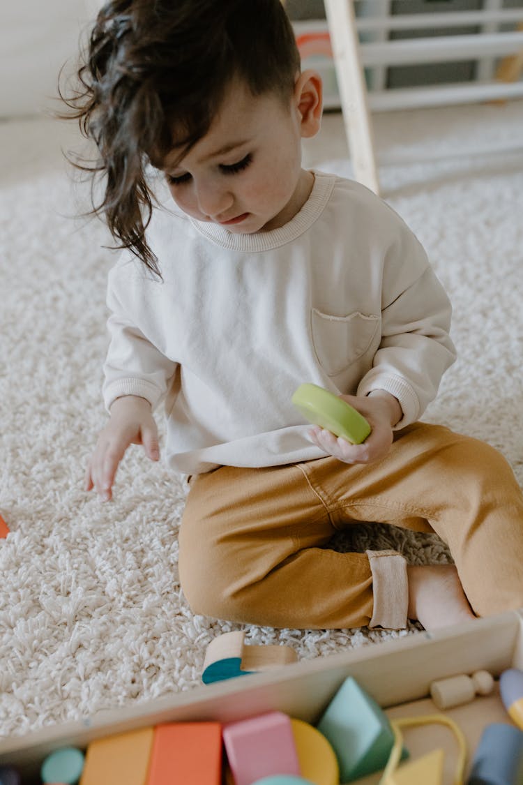 A Kid Playing Wooden Toys On The Carpet