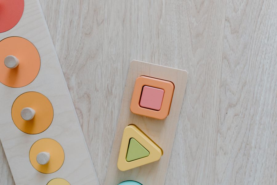 Medinė geometrinių formų dėlionė ant šviesaus stalo