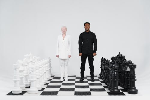 Man and Woman Standing on Giant Chessboard