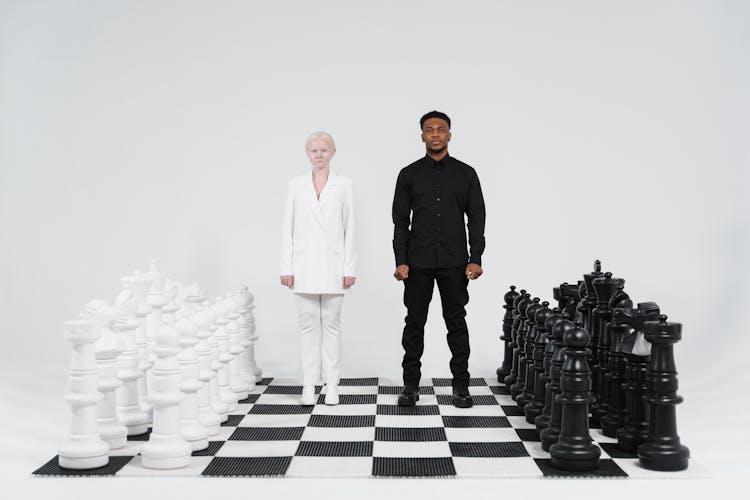 Man And Woman Standing On Giant Chessboard