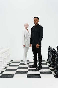 Two individuals stand on a giant chessboard, symbolizing strategy and rivalry.