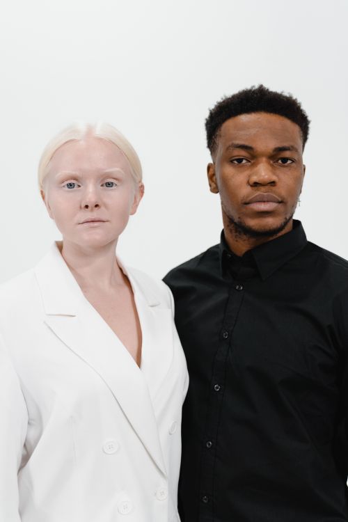 Free Portrait of an albino woman and a black man standing together in formal attire. Stock Photo