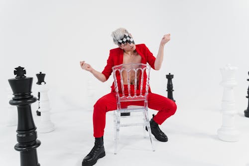 Man in a Red Suit Sitting on the Chair with Chess Pieces