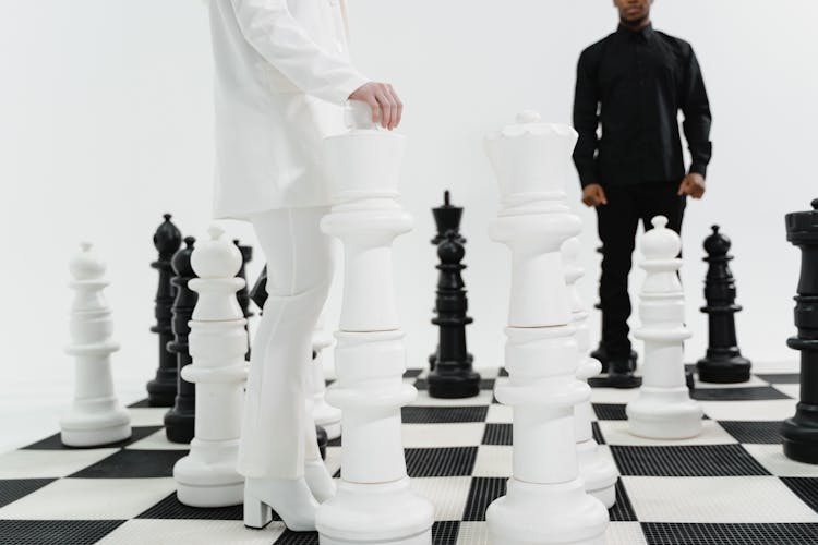 Woman In White Suit Holding A Giant Chess Piece