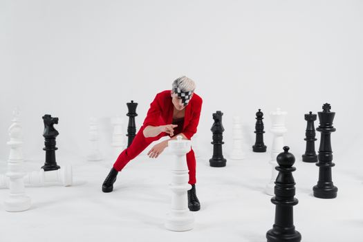 A Man in a Red Suit with Face Makeup Playing with Giant Chess Pieces