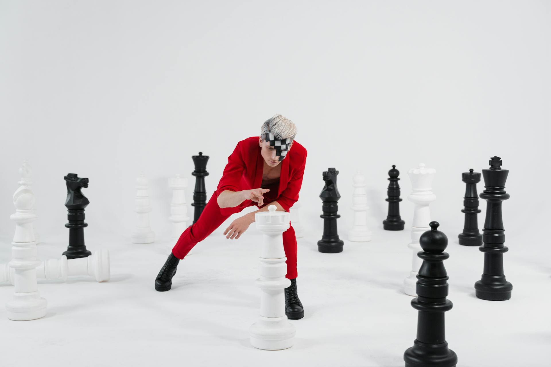 A Man in a Red Suit with Face Makeup Playing with Giant Chess Pieces