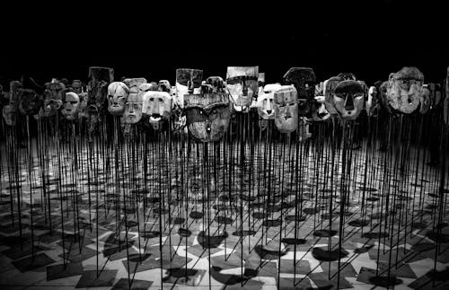 Greyscale Photo of Masks on a Stick