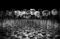 Greyscale Photo of Masks on a Stick