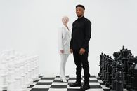 Man and Woman Standing on Giant Chessboard