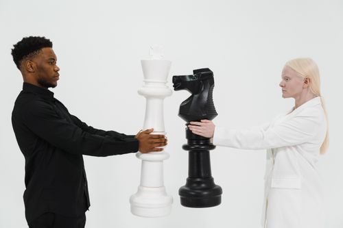 Free Two individuals holding giant chess pieces symbolizing strategy and competition. Stock Photo