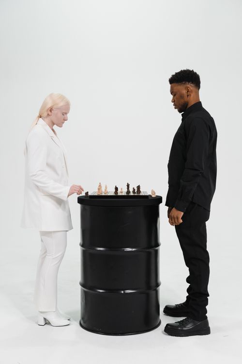 Free Two adults playing chess on a barrel, symbolizing strategic thinking and competition. Stock Photo