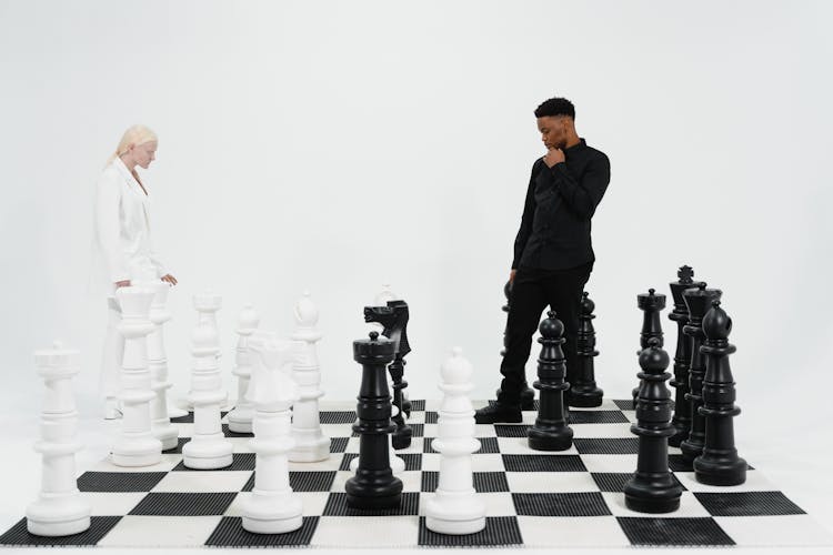 Two People Standing On A Giant Chess Board