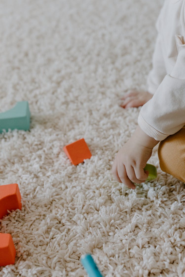 A Kid Playing Wooden Toys On The Carpet