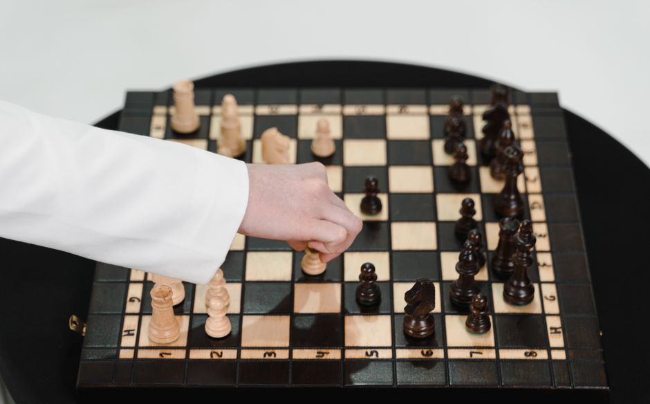 Chess board symbolizing strategic navigation - Florida Bar professional conduct Hand moving a chess piece on a wooden chessboard, illustrating strategic decision-making relevant to legal compliance and professional conduct in the legal field.