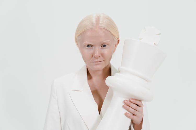 A Woman Holding A White Giant Chess Piece