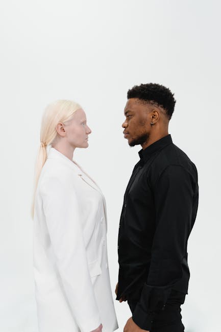 A man and woman stand facing each other on a white background, creating visual contrast.