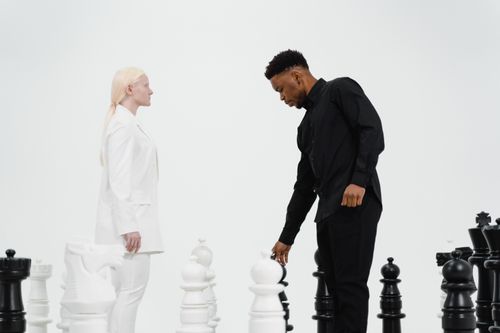 Free Two adults strategizing with oversized chess pieces, emphasizing competition and intellect. Stock Photo