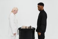 Man and Woman Standing Near a Chess Board on Table