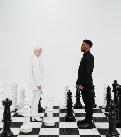 Free Two people represent opposing chess strategies on a life-sized chessboard. Stock Photo