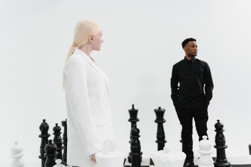 Free Two adults engage with a life-sized chess set, symbolizing strategy and leadership. Stock Photo