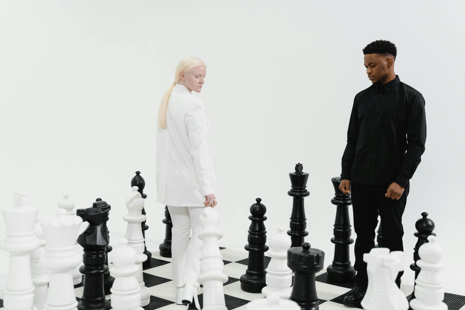 A Woman in White Blazer and a Man in Black Long Sleeves on a Giant Chessboard