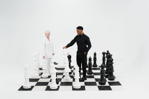 Free A creative indoor setting showcasing a diverse pair engaged in a giant chess game symbolizing strategy and teamwork. Stock Photo