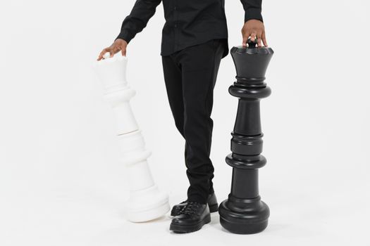 A man stands with large black and white chess pieces, symbolizing strategy and decision-making.