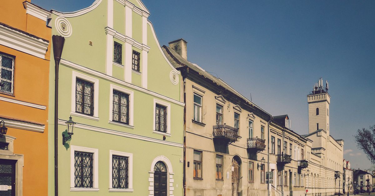 Colorful historic buildings line a quaint European street under a clear blue sky.