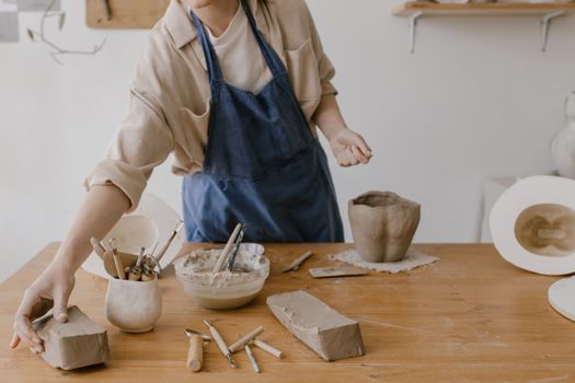A woman working on pottery in a workshop, showcasing artisan tools and clay.